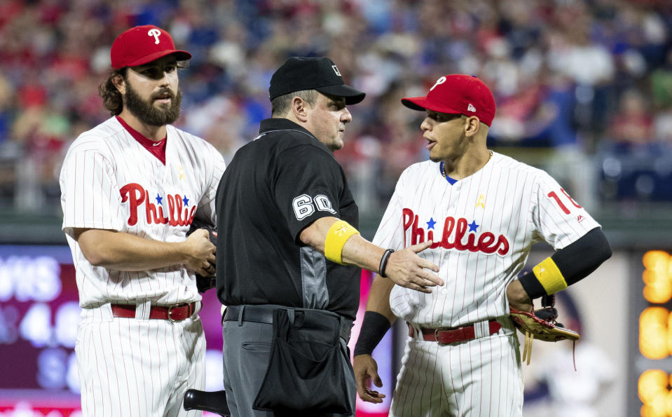 Phillies relief pitcher Austin Davis and second baseman Cesar Hernandez talk with umpire Marty Foster during the eighth inning against the Cubs on Saturday in Philadelphia. Umpire Joe West confiscated a card from Davis, while Davis and manager Gabe Kapler said he was using the card merely for information on the Cubs hitters. (AP Photo/Chris Szagola)