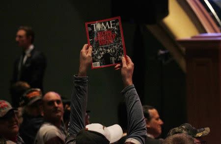 A supporter holds up a copy of Time Magazine with the cover headline "How Trump Won" during Trump's speech at a veteran's rally in Des Moines, Iowa January 28, 2016. REUTERS/Rick Wilking/Files