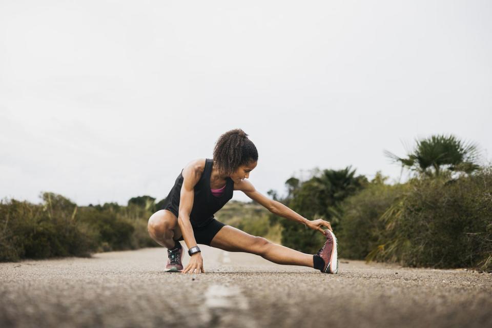 female runner stretching on an empty road woman with fit body warming up on an empty road