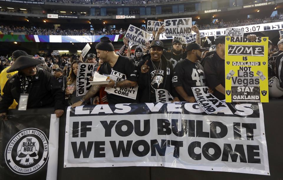 FILE - In this Nov. 6, 2016, file photo, Oakland Raiders fans hold up signs about the team's possible move to Las Vegas during an NFL football game between the Raiders and the Denver Broncos in Oakland, Calif. The Raiders have filed paperwork to move to Las Vegas. Clark County Commission Chairman Steve Sisolak told The Associated Press on Thursday, Jan. 19, 2017, that he spoke with the Raiders. (AP Photo/Marcio Jose Sanchez, File)