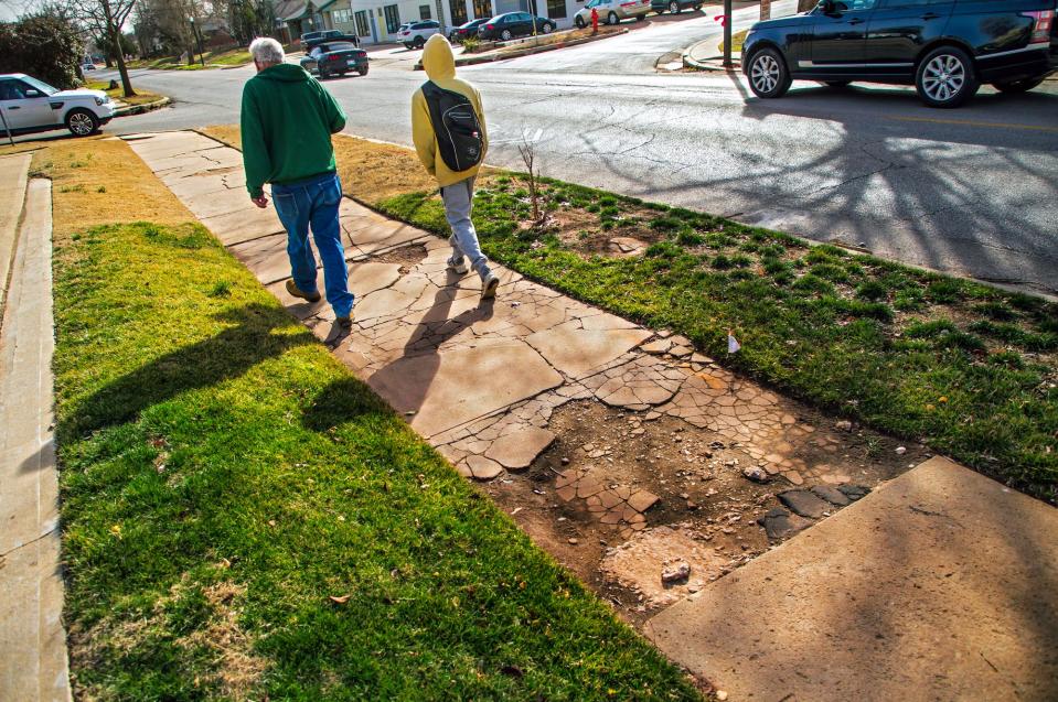 Pedestrians walk along a deteriorating portion of sidewalk Tuesday, Feb. 14, 2023, along Walker Avenue in Oklahoma City.