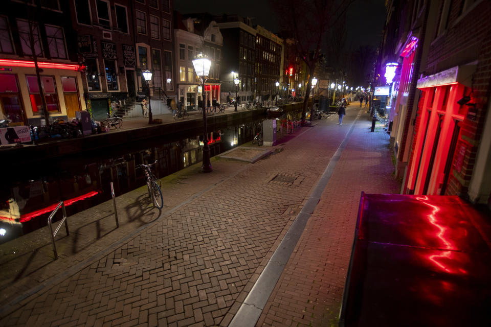 View of the near-empty Red Light District in Amsterdam, Netherlands, Sunday, March 15, 2020, after a TV address of health minister Bruno Bruins who ordered all Dutch schools, cafes, restaurants, including coffeeshops, brothels, strip clubs and sport clubs to be closed from Sunday onwards as the government sought to prevent the further spread of coronavirus in the Netherlands. For most people, the new coronavirus causes only mild or moderate symptoms, such as fever and cough. For some, especially older adults and people with existing health problems, it can cause more severe illness, including pneumonia. (AP Photo/Peter Dejong)