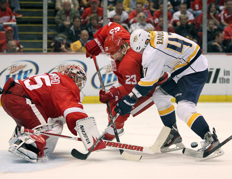 DETROIT, MI - APRIL 15: Jimmy Howard #35 of the Detroit Red Wings keeps an eye on the puck behind teammate Brad Stuart #23 and Alexander Radulov #47 of the Nashville Predators during Game Three of the Western Conference Quarterfinals during the 2012 NHL Stanley Cup Playoffs at Joe Louis Arena on April 15, 2012 in Detroit, Michigan. Nashville won the game 3-2 and lead the series 2-1. (Photo by Gregory Shamus/Getty Images)