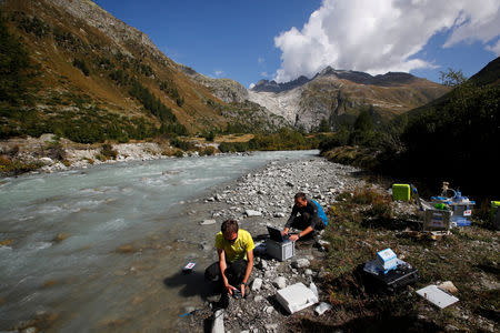 Hannes Peter of the Alpine and Polar Environment Research Center (Alpole) from the Ecole Polytechnique Federale de Lausanne (EPFL) and a colleague perform analyses after collecting microorganisms from a stream to extract their DNA to better understand how they have adapted to their extreme environment, near the Rhone Glacier in Furka, Switzerland, September 13, 2018. REUTERS/Denis Balibouse