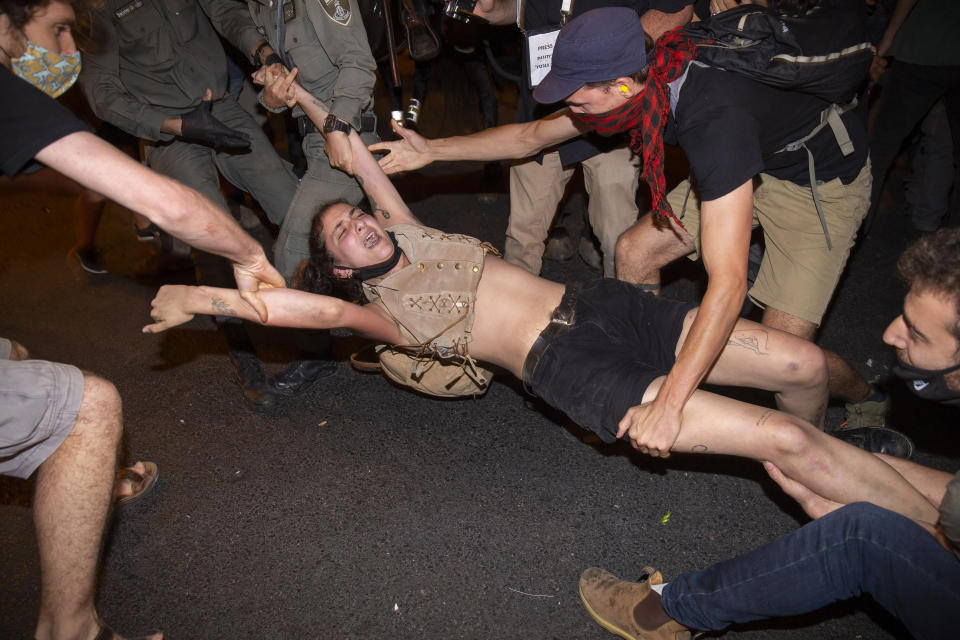 Israeli police scuffle with demonstrators during a protest against Israel's Prime Minister Benjamin Netanyahu outside his residence in Jerusalem, early Wednesday, July 22, 2020. Protesters demanded that the embattled leader resign as he faces a trial on corruption charges and grapples with a deepening coronavirus crisis. (AP Photo/Ariel Schalit)