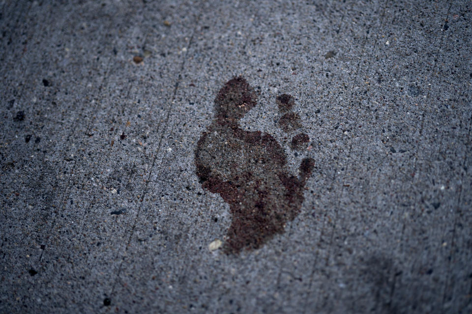 A bare bloody footprint remains on the sidewalk in the 2900 block of Hennepin Avenue after an early morning shooting, Sunday, June 21, 2020, in Minneapolis' Uptown neighborhood. The shooting in the popular nightlife area early Sunday left one man dead and multiple people wounded in a chaotic scene that sent people ducking into restaurants and other businesses for cover. (Jerry Holt/Star Tribune via AP)