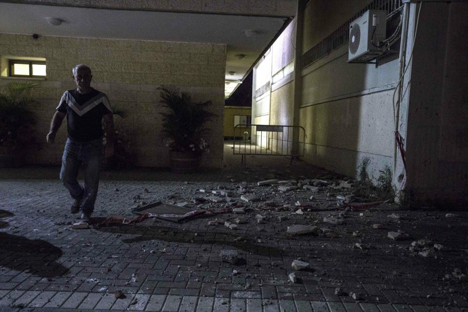 A man stands outside a Jewish religious school in Sderot, Israel, after it was hit by a rocket fired from the Gaza Strip, Thursday, June 13, 2019. (AP Photo/Tsafrir Abayov)
