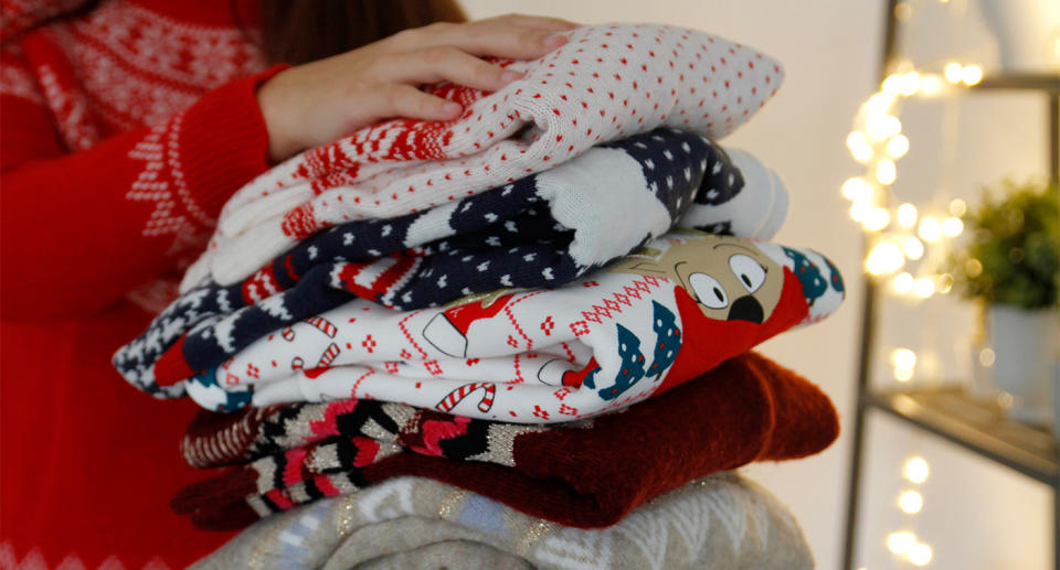 Woman holding Christmas jumpers. (Getty Images)