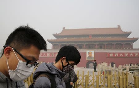 People wearing masks walk past the giant portrait of late Chinese Chairman Mao Zedong, at the Tiananmen Gate during a heavily polluted day in Beijing, November 30, 2015. REUTERS/Kim Kyung-Hoon