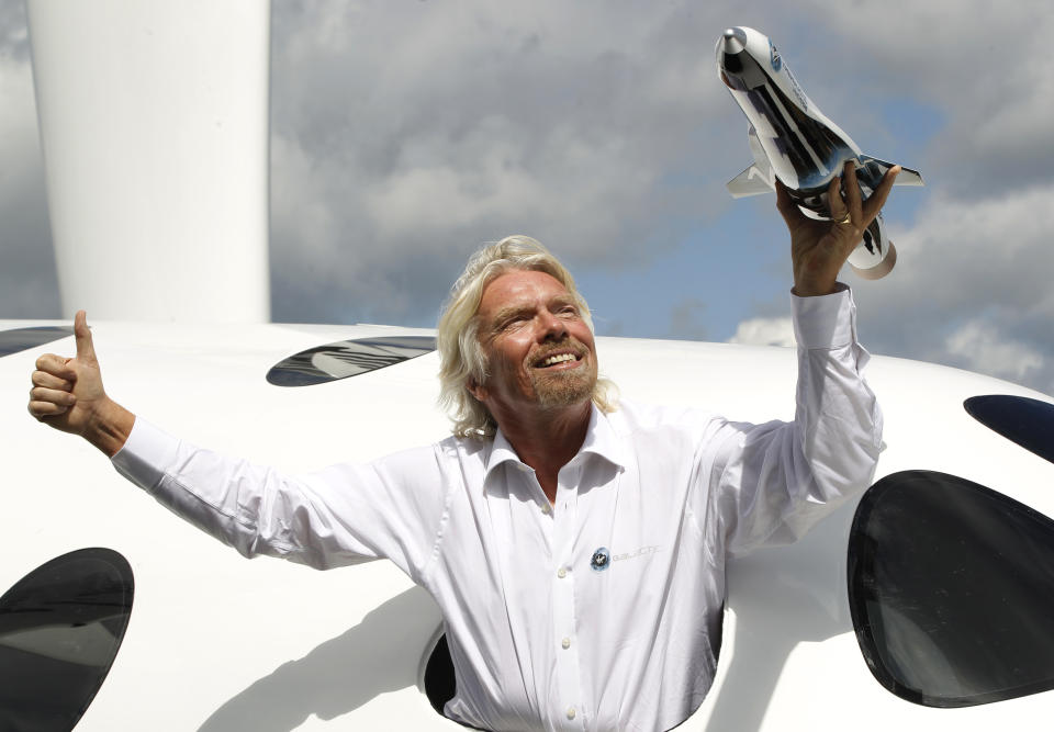Sir Richard Branson poses for the photographers in the window of a replica of the Virgin Galactic, which according to the company will be the world’s first commercial spaceline, at the Farnborough International Airshow in Farnborough, England, Wednesday, July 11, 2012. Branson also revealed a plan to launch small satellites into space at a tenth of the current cost. (AP Photo/Lefteris Pitarakis)