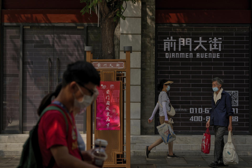 Visitors wearing face masks tour past vacant shop lots at Qianmen Street in Beijing, Wednesday, Aug. 17, 2022. Factories in China's southwest have shut down after reservoirs used to generate hydropower ran low in a worsening drought, adding to economic strains at a time when President Xi Jinping is trying to extend his position in power. (AP Photo/Andy Wong)