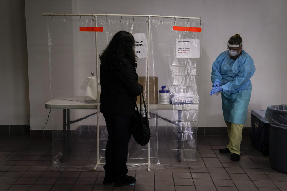 Registered nurse Leslie Clark, right, puts on a new pair of protective gloves to collect a nasal swab sample at a COVID-19 testing site in Los Angeles, Sunday, Dec. 27, 2020. Hospitals in central and Southern California are quickly running out of intensive care unit beds for coronavirus patients and state officials are poised to extend the strictest stay-at-home orders there as conditions worsen before the post-holiday surge hits. (AP Photo/Jae C. Hong)