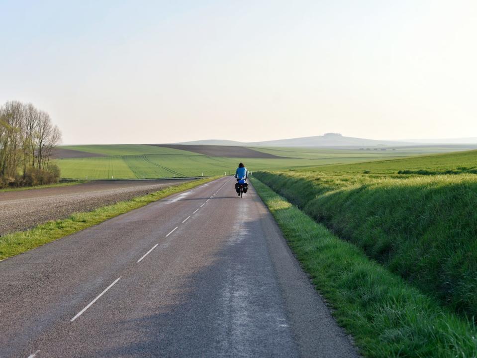 Joshua Kian riding a bike on a paved road surrounded by green rolling hills.