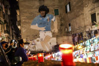 People light candles to honor Diego Maradona, in Naples, Italy, Wednesday, Nov. 25, 2020. Diego Maradona has died. The Argentine soccer great was among the best players ever and who led his country to the 1986 World Cup title before later struggling with cocaine use and obesity. He was 60. (Alessandro Garofalo/LaPresse via AP)