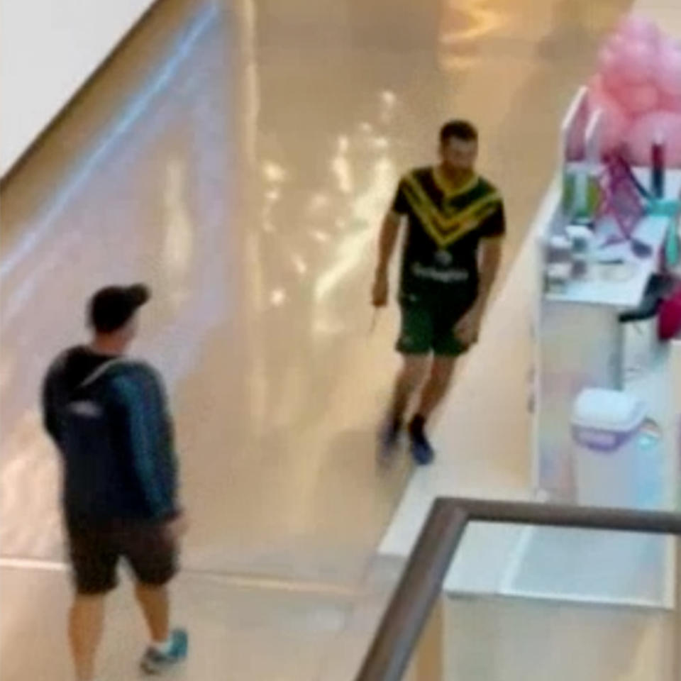 A knifeman in a green and yellow rugby jersey holds a knife in Bondi Junction Westfield