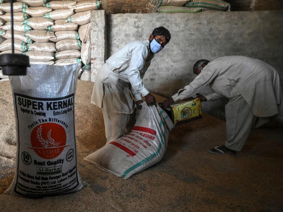 In this picture taken on March 31, 2021 workers fill a sack with rice at the Al-Barkat Rice Mills on the outskirts of Lahore. - From biryani to pilau, Pakistan and India's shared culinary landscape is defined by basmati, a distinctive long-grain rice now at the centre of the latest tussle between the bitter rivals.