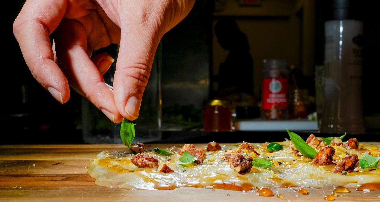 Basil is placed on a butter board at Charcuter-Me, 770 N. Jefferson St. The board also holds honey butter, candied pecans, hot honey, red chile flakes, lemon zest, sea salt and edible flowers, served with baguette.