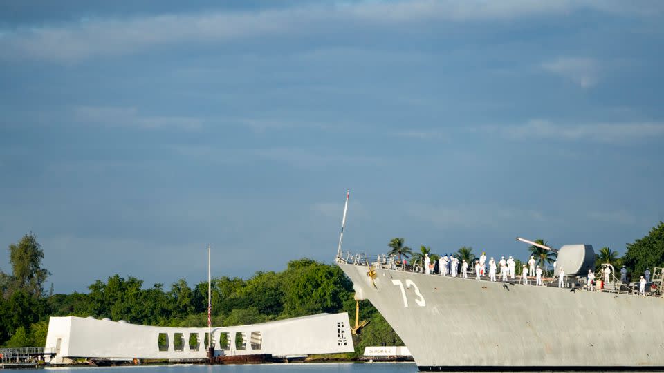 Sailors aboard the the USS Decatur render honors while passing the USS Arizona Memorial and the sunken battleship the USS Arizona during the 82nd Pearl Harbor Remembrance Day ceremony on Thursday, December 7, 2023, at Pearl Harbor in Honolulu, Hawaii. - Mengshin Lin/AP