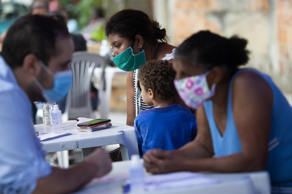 Residents receive medical attention during a campaign organized by doctors and volunteers amid the new coronavirus pandemic in the Chapadao favela in Rio de Janeiro, Brazil, Saturday, Oct. 17, 2020. The residents received health assistance, protective face masks, legal advise and food as part of the campaign. (AP Photo/Bruna Prado)