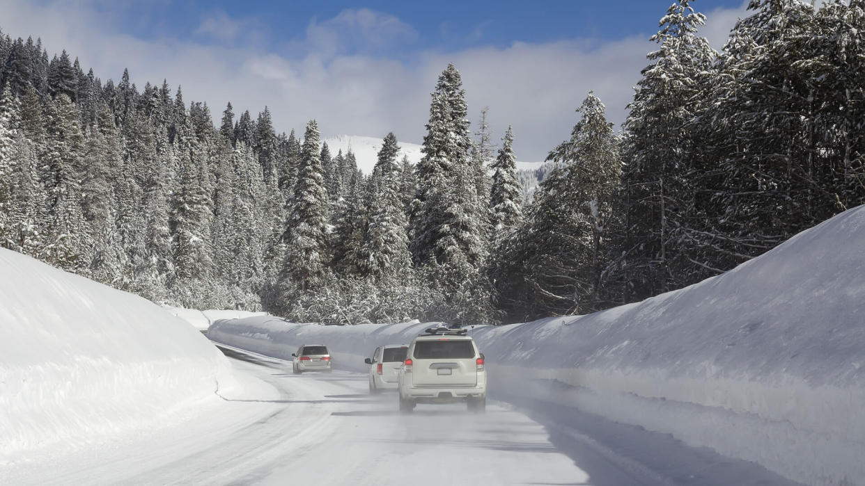 Winter landscape with cars on the road in snowy forest.