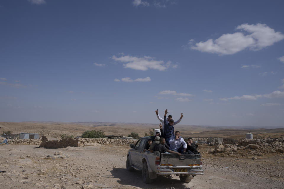 Palestinian labors waves their hands to reporters as they ride at the back of pickup truck and heading to work, in the West Bank Beduin community of Jinba, Masafer Yatta, Friday, May 6, 2022. Israel's Supreme Court has upheld a long-standing expulsion order against eight Palestinian hamlets in the occupied West Bank, potentially leaving at least 1,000 people homeless. (AP Photo/Nasser Nasser)