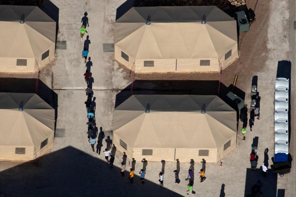 Immigrant children are led by staff in single file between tents at a detention facility next to the Mexican border (REUTERS)