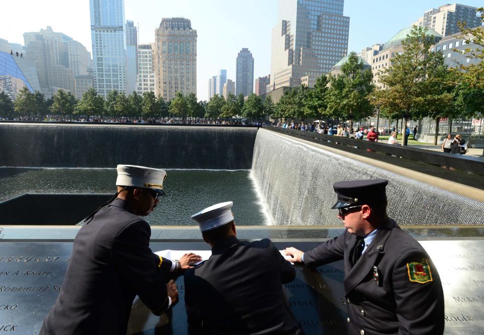 Volunteer firefighters (L to R) Lt. Carlos Santiago, Capt. Alex Avallon and Assistant Engineer Eric Robertson of the Enterprise Hose Company in Hatboro, Pennsylvania stop to remember the victims of Flight 11 at the 9/11 Memorial during a ceremony marking the 12th Anniversary of the attacks on the World Trade Center in New York September 11, 2013. (REUTERS/David Handschuh)