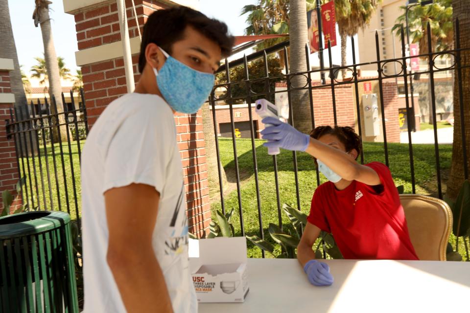 LOS ANGELES, CA - AUGUST 17, 2020 - - Anthony Steimle, 21, left, has his temperature checked by Campus Health and Screening Ambassador Avery Theus, 23, on the first day of academic instruction at USC for the Fall 2020 semester in Los Angeles on August 17, 2020.  Steimle, not a student at USC, was visiting the campus with his brother. All students and visitors to the campus have to go through a wellness check, answer questions regarding COVID-19 symptoms and have their temperature checked before they are allowed to enter campus. (Genaro Molina / Los Angeles Times via Getty Images)