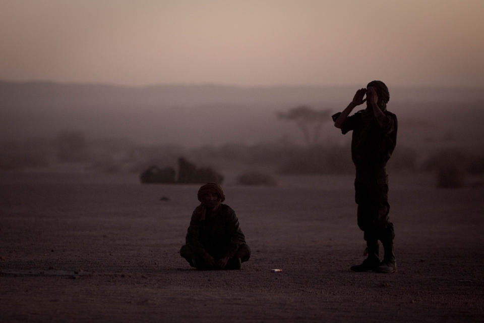 FILE - In this Feb.27, 2011 file photo, pro-independence Polisario Front rebel soldiers pray after sunset in the Western Sahara village of Tifariti. The Moroccan military has intervened in a U.N.-patrolled border zone in the disputed Western Sahara to clear a key road it said was being blockaded for weeks by supporters of the pro-independence Polisario Front. Moroccan forces set up a security cordon overnight in the Guerguerat buffer zone on Western Sahara's southern border with Mauritania, "in order to secure the flow of goods and people through this axis," (AP Photo/Arturo Rodriguez, File)