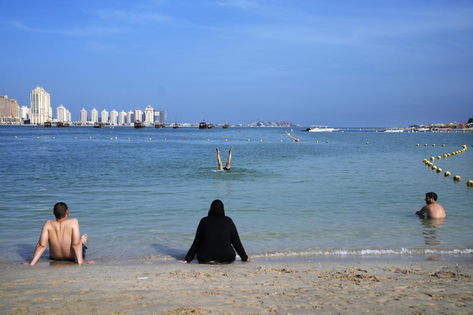 People sit and swim at Katara Beach, in Doha, Qatar, Thursday, Dec. 1, 2022. (AP Photo/Jorge Saenz)