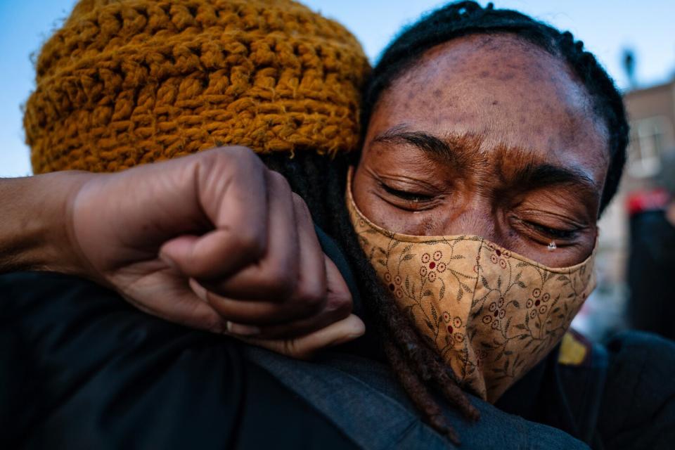 A woman hugs a person and cries.