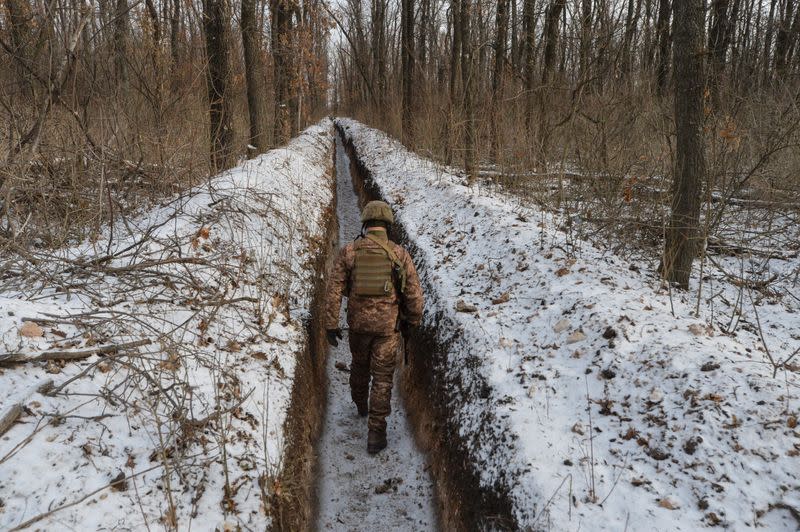 FILE PHOTO: A Ukrainian service member walks along fighting positions near Avdiivka