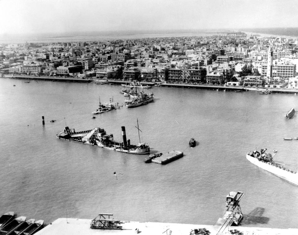 FILE - In this Nov. 19, 1956 file photo, scuttled ships at the entrance to the Suez Canal, at Port Said, as seen from over Port Fuad, Egypt. Since it opened in 1869, the canal has been a source of national pride and a focus of international conflict. Now, a skyscraper-sized container ship called the Ever Given got stuck sideways across the waterway since Tuesday, March 23, 2021 . The obstruction has halted canal traffic, valued at over $9 billion a day. (AP Photo, File)