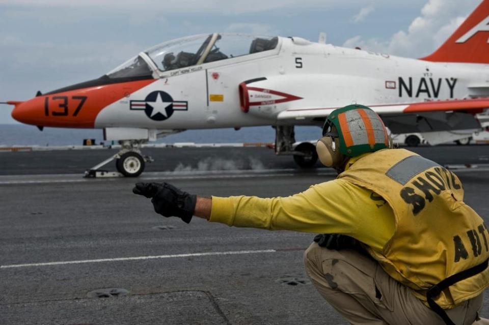 A US Navy catapult and arresting gear officer signals for the launch of a T-45C Goshawk training aircraft