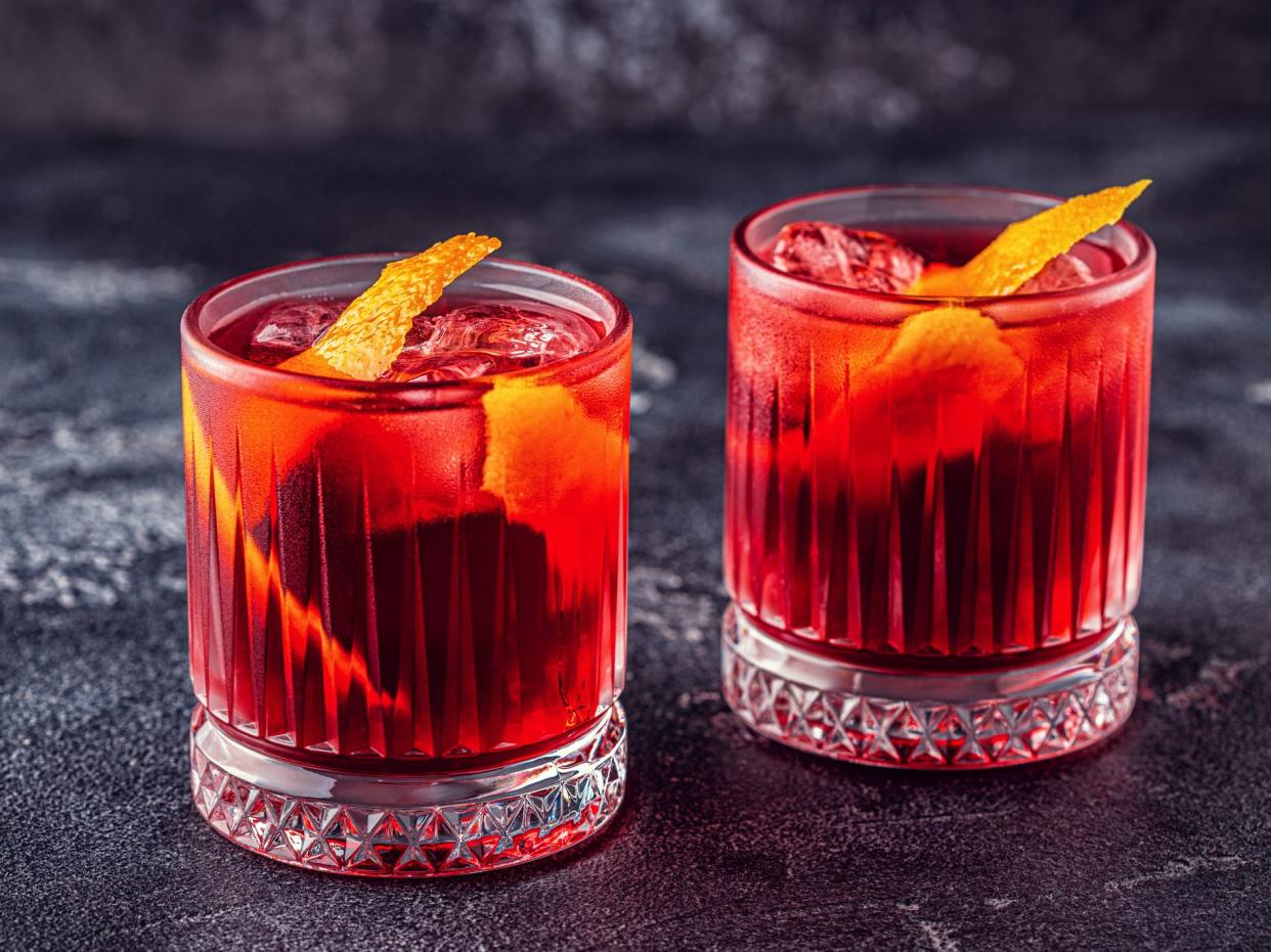 Negroni cocktail with orange peel and ice, selective focus.