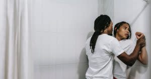 Black man pinning a Black woman against the wall.