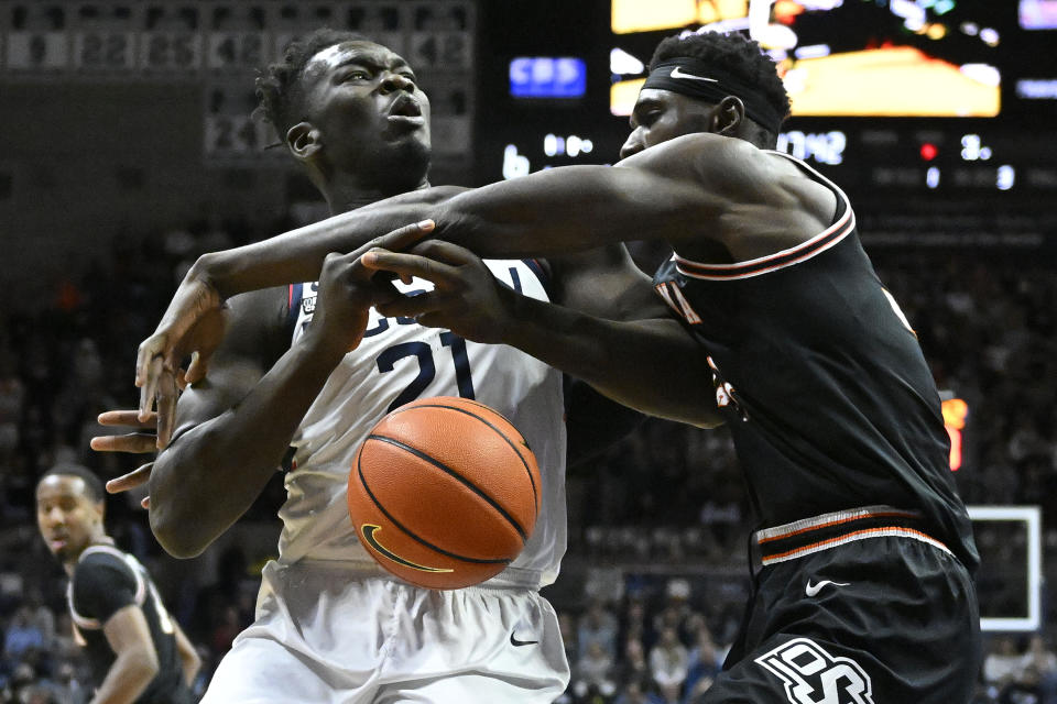 Connecticut's Adama Sanogo (21) is fouled by Oklahoma State's Moussa Cisse, right, in the first half of an NCAA college basketball game, Thursday, Dec. 1, 2022, in Storrs, Conn. (AP Photo/Jessica Hill)