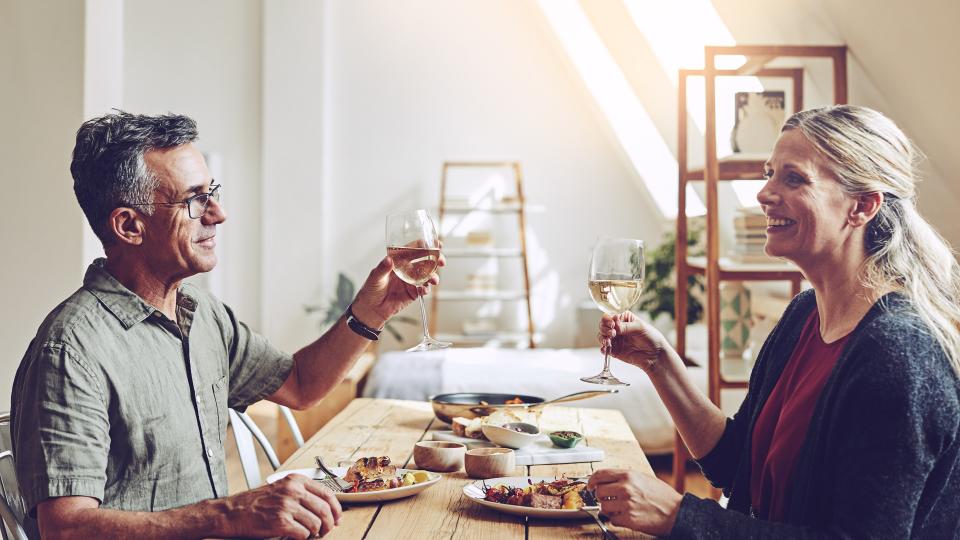 Shot of a mature couple having a meal by the dining room table at home.