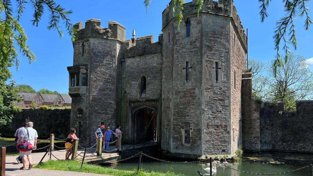 The Bishop's Palace in Wells seen from the outside with people standing on the drawbridge