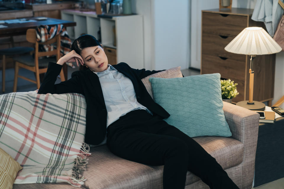 Taiwanese lady in suit sagging wearily back in sofa is out of energy. asian businesswoman is staring blankly with hand propping her head, too tired to say a word or do anything