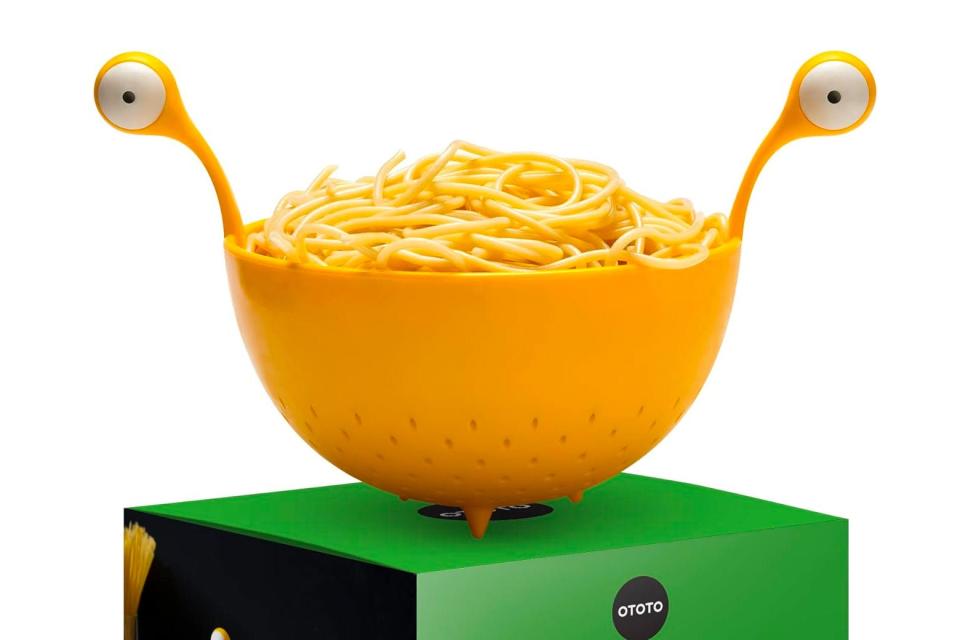 The colander is yellow and has handles that are eyes on stalks.