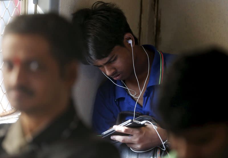 FILE PHOTO: A man watches a video on his mobile phone as he commutes by a suburban train in Mumbai