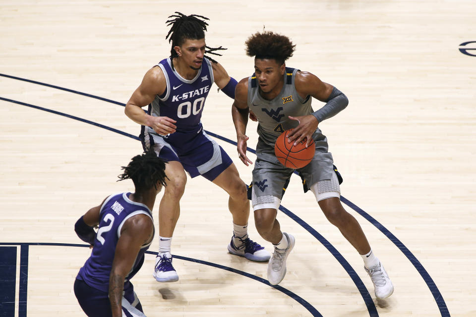 West Virginia guard Miles McBride (4) is defended by Kansas State guards Mike McGuirl (0) and Selton Miguel (2) during the first half of an NCAA college basketball game Saturday, Feb. 27, 2021, in Morgantown, W.Va. (AP Photo/Kathleen Batten)