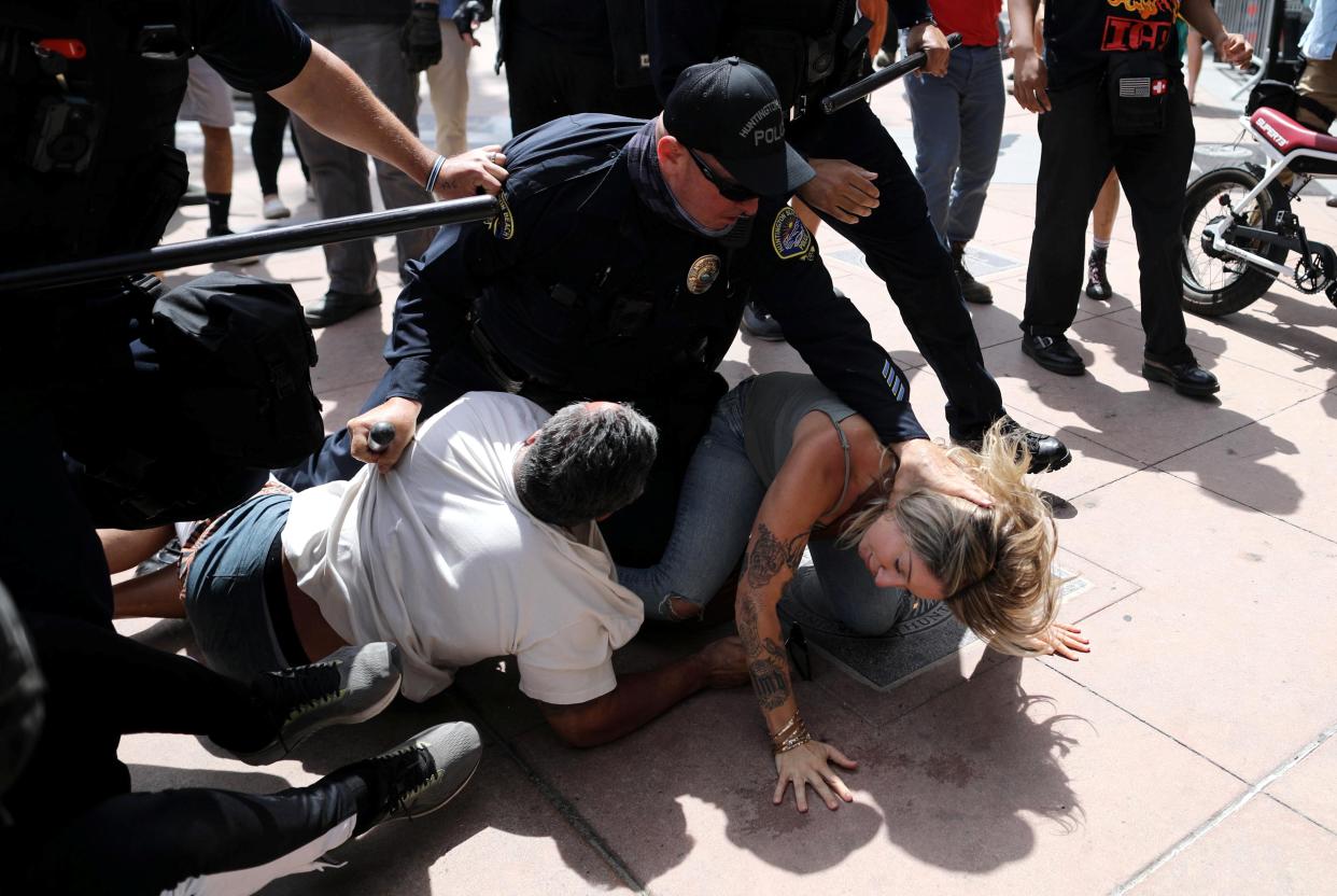 <p>A police officer pins a woman down during confrontations with protesters in Huntington Beach</p> (REUTERS)