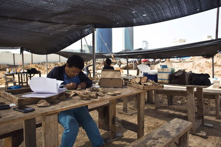 A worker for the Israel Antiquities Authority (IAA) cleans findings at an archaeological dig in a future construction site in Tel Aviv, where fragments of ancient basins were unearthed, March 29, 2015. REUTERS/Nir Elias