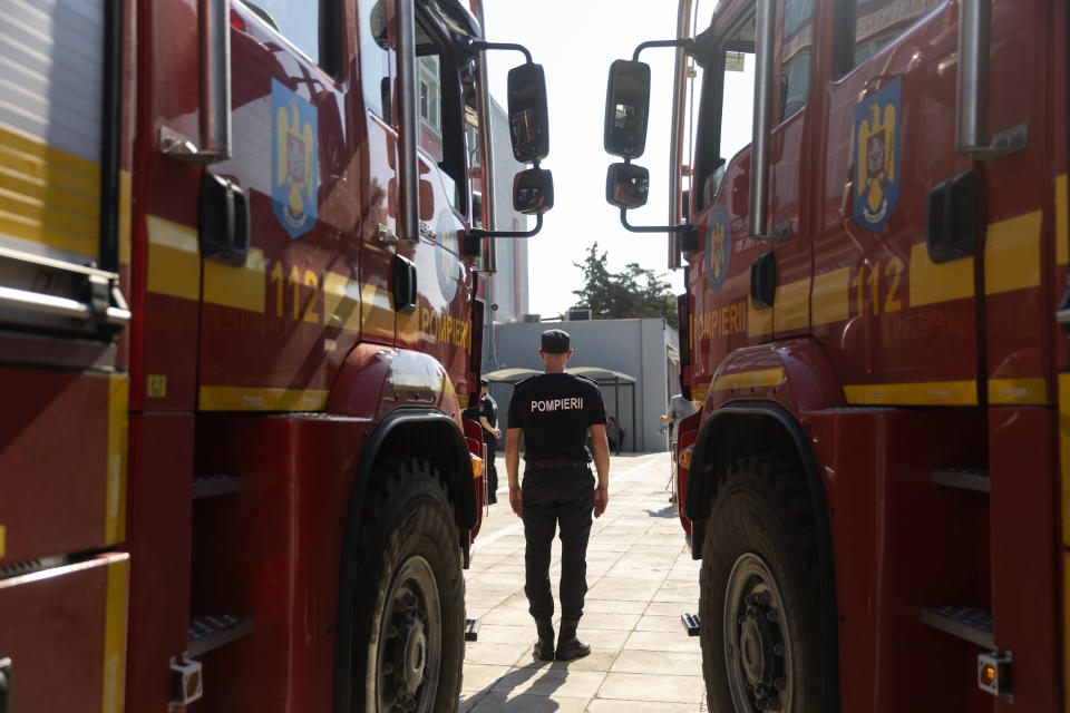 A Romanian firefighter stands in front of a fire engine during a ceremony, in Athens, on Saturday, July 2, 2022. Twenty eight Romanian firefighters, the first of more than 200 firefighters from other European countries that will help their Greek colleagues in fighting wildfires, were welcomed by Climate Crisis and Civil Protection Minister Christos Stylianides and the leadership of Greece's Fire Service. (AP Photo/Yorgos Karahalis)