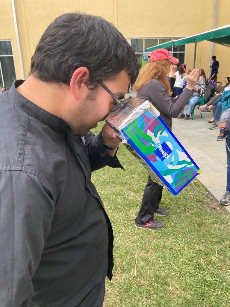 Sunjay Kulkacek a middle school science teacher at Shue-Medill Middle School uses a homemade viewer to look at the eclipse during the Delaware Museum of Nature and Science eclipse viewing party on April 8, 2024.