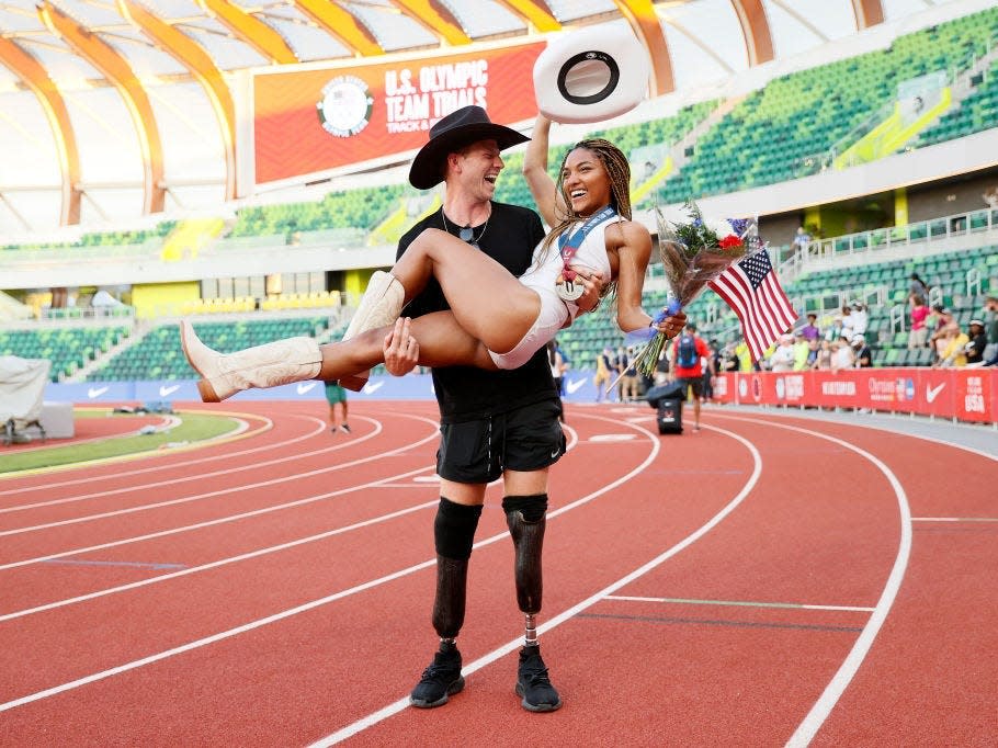 Hunter Woodhall holds girlfriend Tara Davis in his arms on a track field