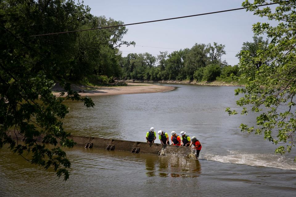 Crews from Synergy Contracting help Des Moines Water Works raise flashboards in the Raccoon River. Low water has repeatedly forced the water works to take the measure over the last few years. Proponents of a unified Central Iowa Water Works say the combined resources of the group would better enable it to address such issues.