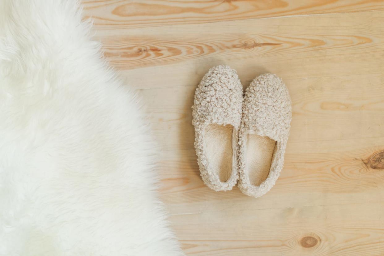 cozy warm fur slippers near fur carpet in a living room